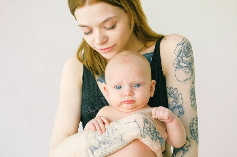 tattooed mom carrying child