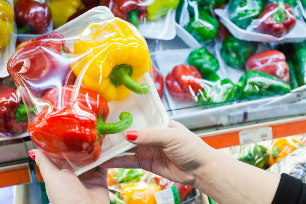Image of packaged bell pepper with woman hand in the supermarket