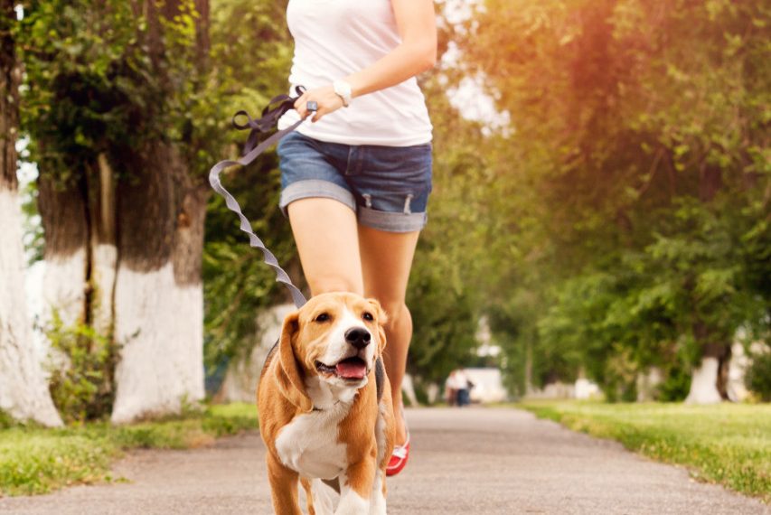 a happy woman running with her dog outside