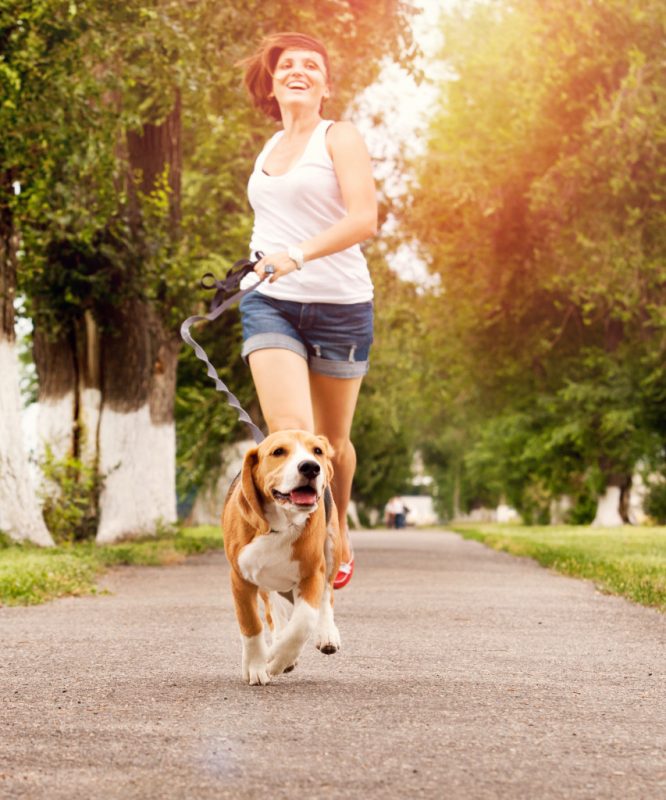 a happy woman running with her dog outside