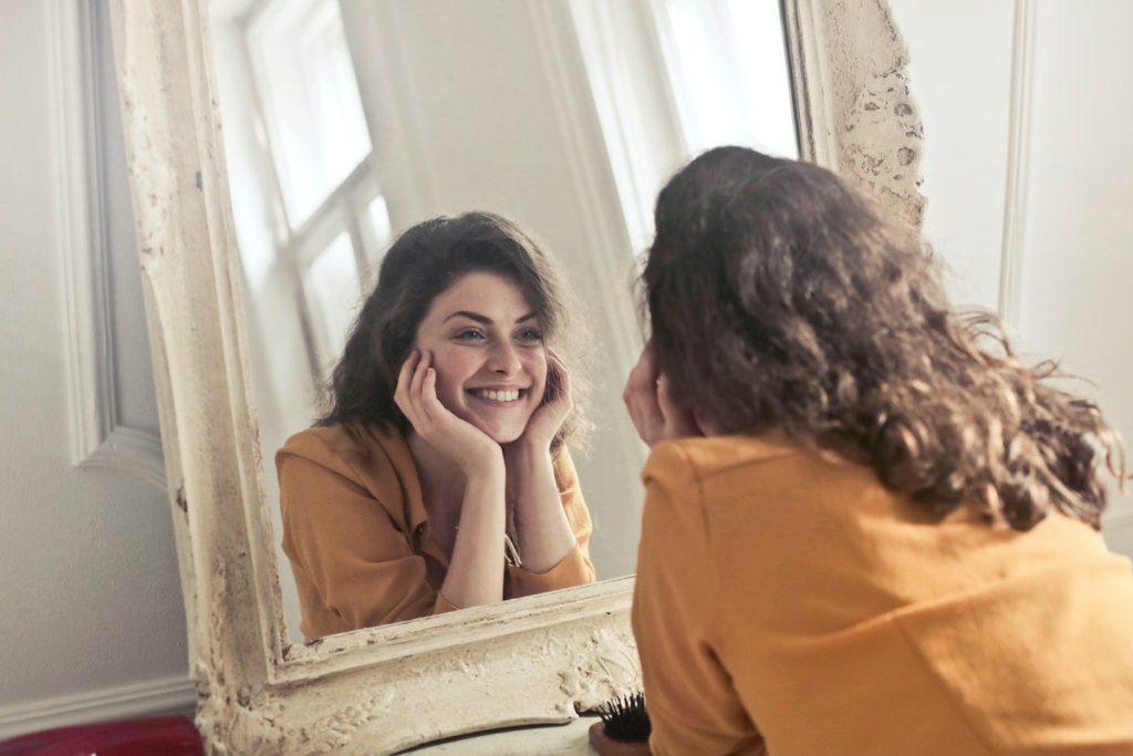 happy woman looking herself on the mirror