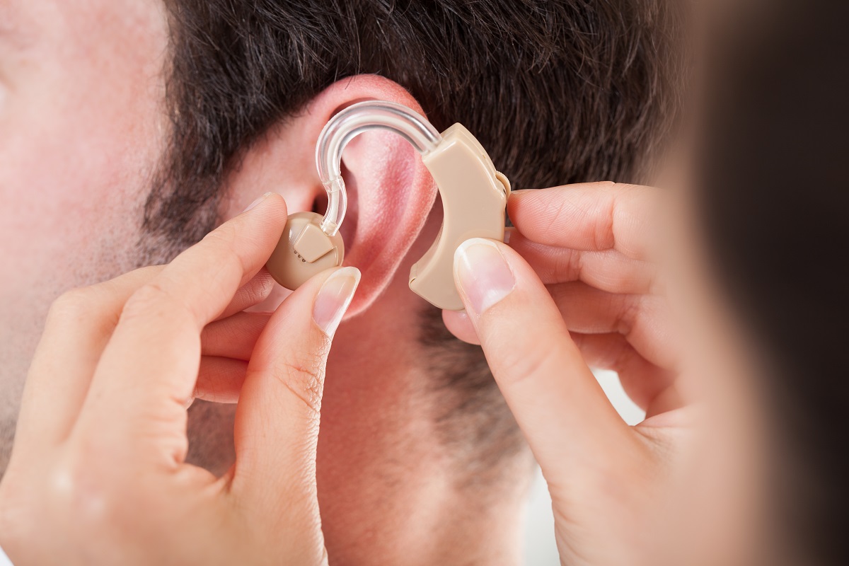 doctor putting a hearing aid on a patient's ear