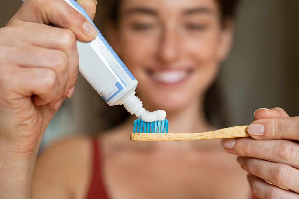 woman putting toothpaste in toothbrush